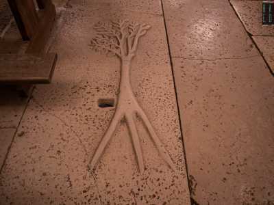 Ma le meraviglie del luogo non finiscono qui. Al centro della navata notiamo sul pavimento una lastra in pietra raffigurante un albero con tre radici e un foro...